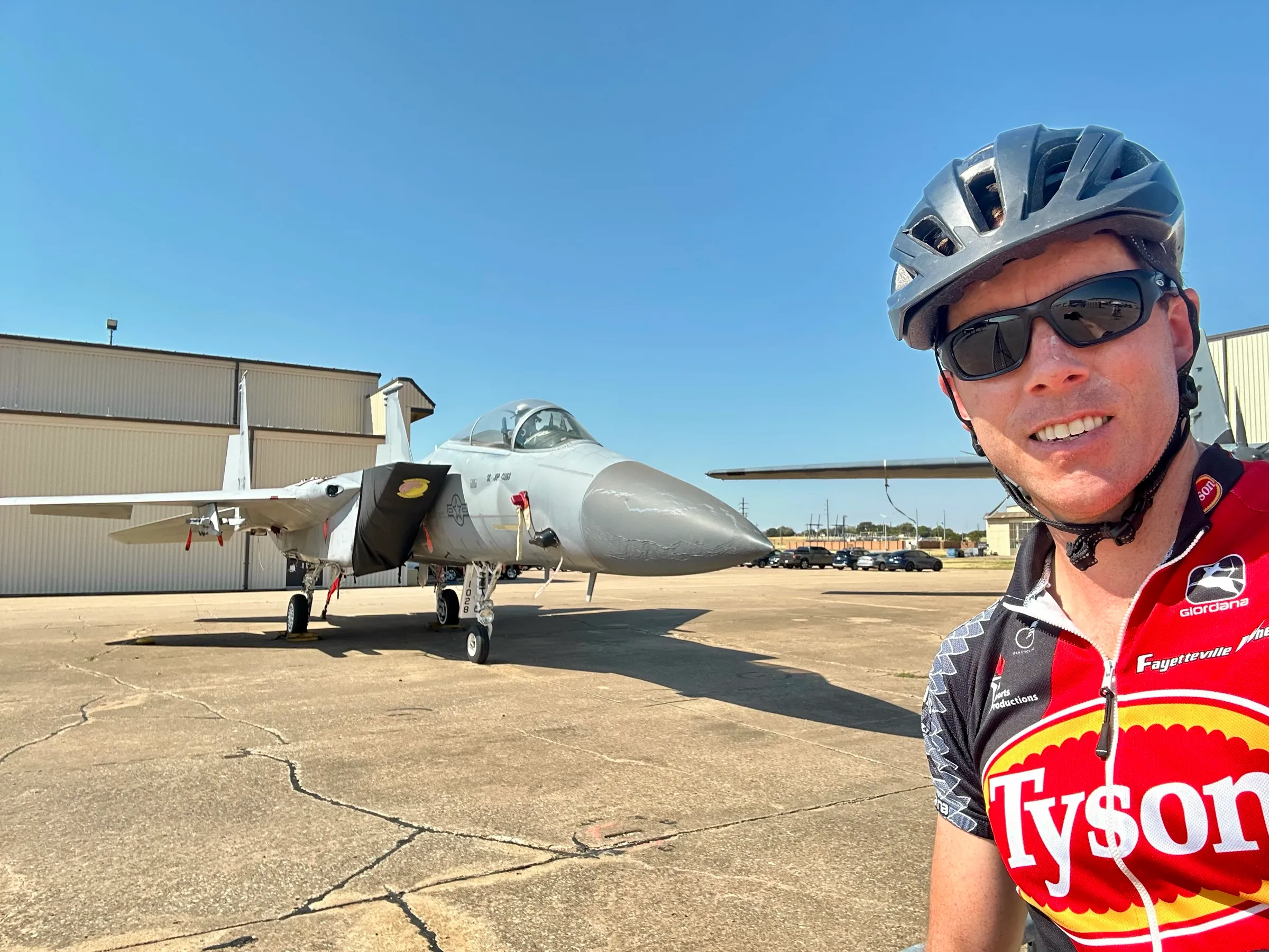 A cyclist poses beside a parked military jet at the Hotter’N Hell Hundred in Wichita Falls.